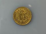 an old gold coin sitting on top of a white surface