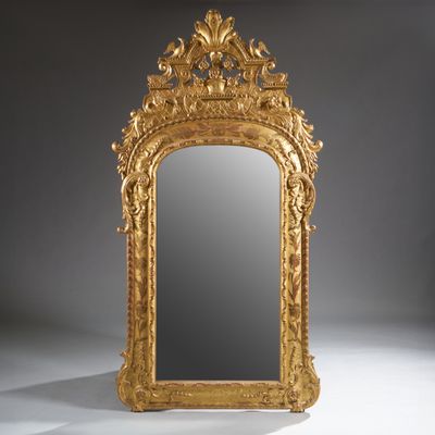 an ornately carved mirror with a gold frame on a white surface