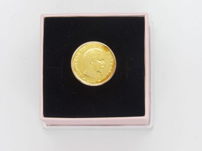un gros plan d'une pièce d'or dans une boîte rose