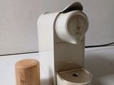une cafetière blanche avec un couvercle en bois, posée à côté d'une tasse