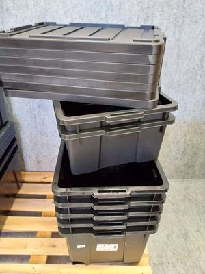 three black plastic containers stacked on top of a wooden pallet