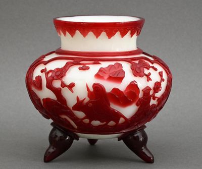 un vase rouge et blanc posé sur un socle en bois