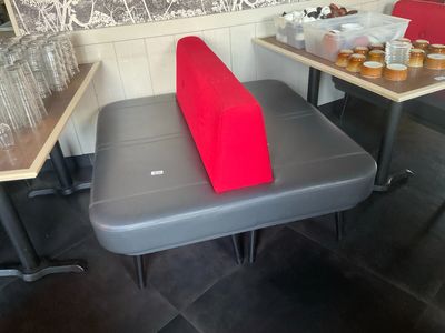 un banc sur lequel est posé un coussin rouge, dans un restaurant