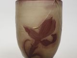 un verre orné d'une fleur, posé sur une surface blanche