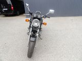 a motorcycle parked in front of a building with a car in the background