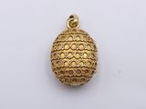 a close up of a gold plated pendant on a white surface