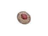 gros plan d'une bague avec une pierre rouge entourée de diamants