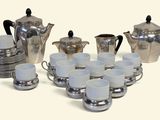 une photo d'un service à café en argent avec des tasses et des soucoupes