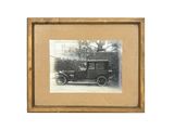 une vieille photo d'un homme assis dans une voiture devant une maison