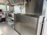 a woman standing in the kitchen of a food truck