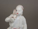 a white figurine of a boy with a bird on his shoulder