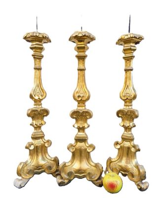 two gold candlesticks with apples on a white background