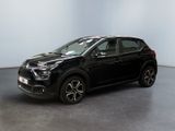 Une voiture noire est garée dans une pièce aux murs blancs.