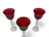 three wine glasses sitting next to each other on a white surface