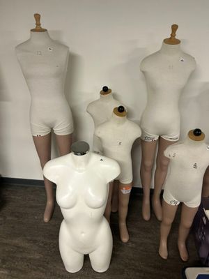 Plusieurs mannequins sont alignés en rang devant un mur blanc