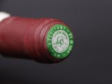 a close up of a bottle of wine with a green cap
