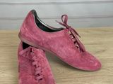 pink sued shoes with laces and bows on them on a wooden table