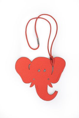 une étiquette à bagages en forme d'éléphant suspendue à une lanière en cuir rouge
