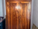 a wooden armoire in the corner of a room with a wicker chair