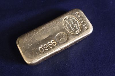 un vieux lingot d'argent posé sur un tissu bleu à fond noir