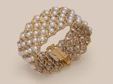 a close up of a gold bracelet with pearls and diamonds