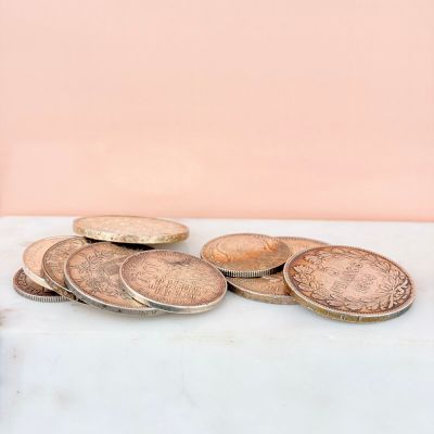 a pile of coins sitting on a table next to a cup of coffee