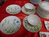 many plates and cups on a table with a red table cloth