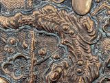 a close up of a metal plate with a dragon on it