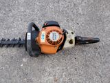 an orange and black hedger sitting on top of a cement ground