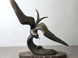 sculpture en bronze représentant un oiseau tenant un poisson dans son bec, posée sur un socle en marbre