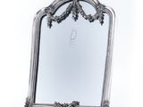 un miroir ancien en argent dont le cadre est orné d'un motif floral