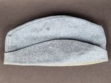 un gros plan d'un chapeau gris posé sur une surface marron