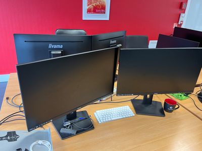 two computer monitors sitting on a desk with a keyboard and mouse