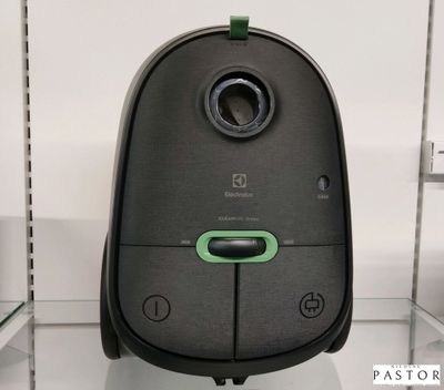 un aspirateur noir et vert posé sur une étagère dans un magasin