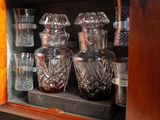 bottles and glasses are sitting on a shelf in a cabinet