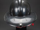 an old fireman ' s helmet on a stand against a black background
