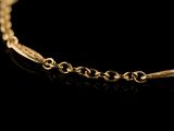 a close up of a gold chain bracelet on a black background