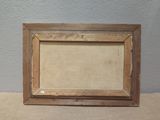 an old picture frame sitting on top of a table next to a wall