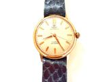 une image représentant une montre en or avec un bracelet violet sur fond blanc
