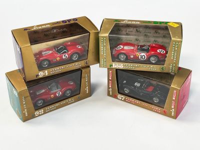 trois petites voitures rouges sont rangées dans des boîtes posées sur une surface blanche