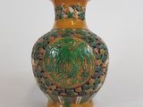 un vase vert et jaune posé sur une surface blanche
