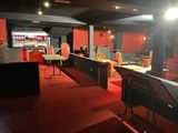 une pièce recouverte de moquette rouge, avec des chaises et des tables rouges