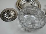 a glass bowl sitting on top of a table next to a silver plate