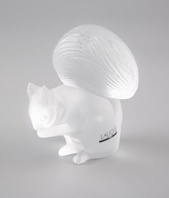 une figurine blanche représentant un écureuil avec une pelote de laine sur le dos
