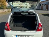 une voiture blanche dont le coffre est ouvert, garée sur un parking