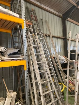 many ladders stacked up in a warehouse area