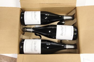 three bottles of wine are in a cardboard box on a table