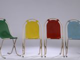 quatre chaises de couleurs différentes sont alignées sur un fond blanc