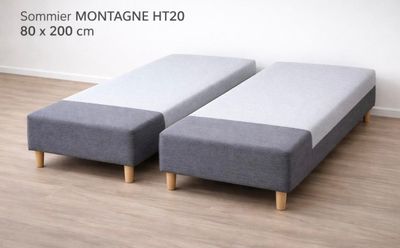 deux poufs gris posés sur un parquet, près d'un mur blanc