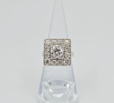 une bague en diamant et en or blanc posée sur un socle en verre transparent